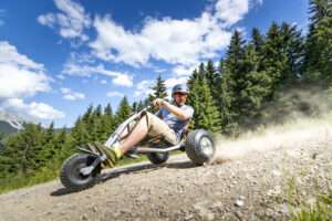 Mann sitzt auf einem Mountaincart und fährt einen Bergweg hinab