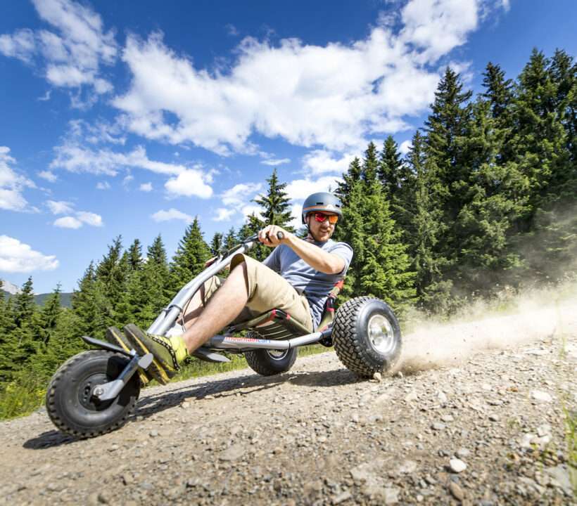 Mann sitzt auf einem Mountaincart und fährt einen Bergweg hinab