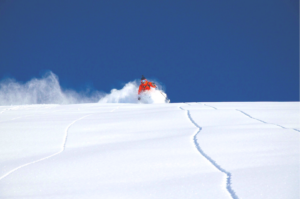 Skifahrer fährt auf einem leerem Hang in unberührtem Tiefschnee