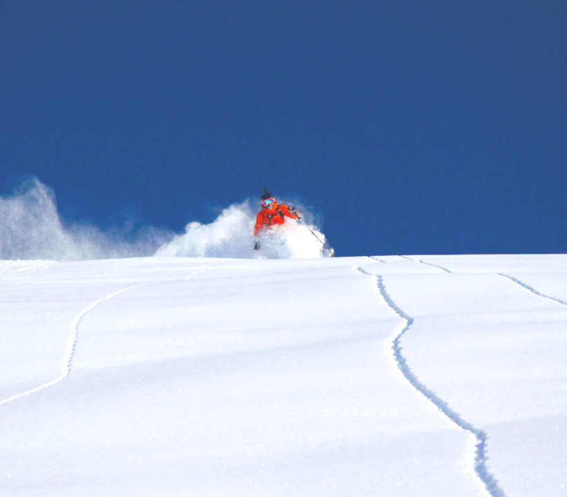 Skifahrer fährt auf einem leerem Hang in unberührtem Tiefschnee