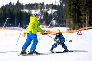 Ein Skilehrer gibt einem Kind im Kinderland Einzelunterricht