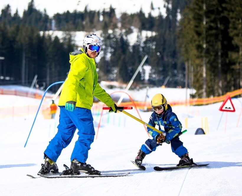 Ein Skilehrer gibt einem Kind im Kinderland Einzelunterricht