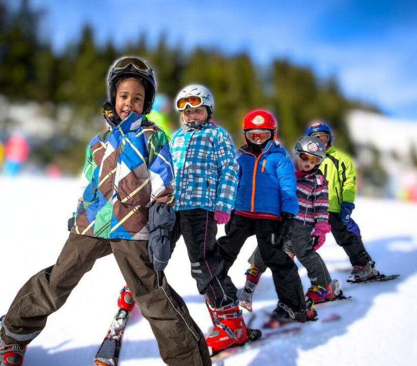 Schulkinder im Schulskikurs bilden eine Kette auf der Piste